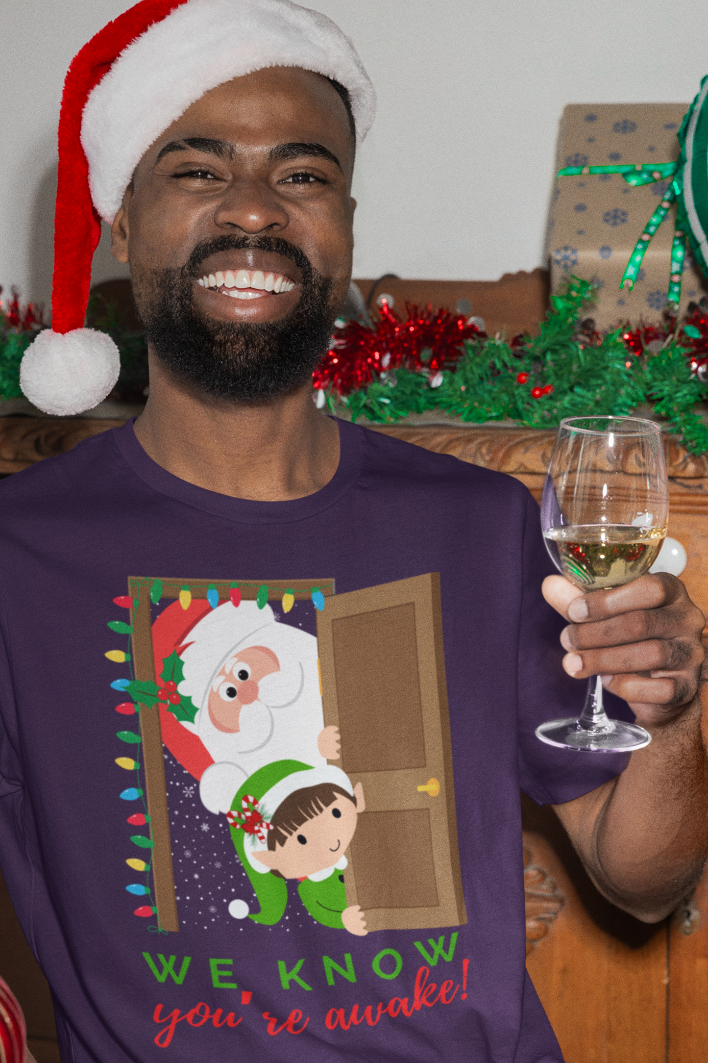 Funny Santa and Elf Christmas Shirt “We Know You’re Awake!” Doorway Peeking Design Holiday Graphic Tee for Him or Her Adult Unisex Jersey Short Sleeve Tee